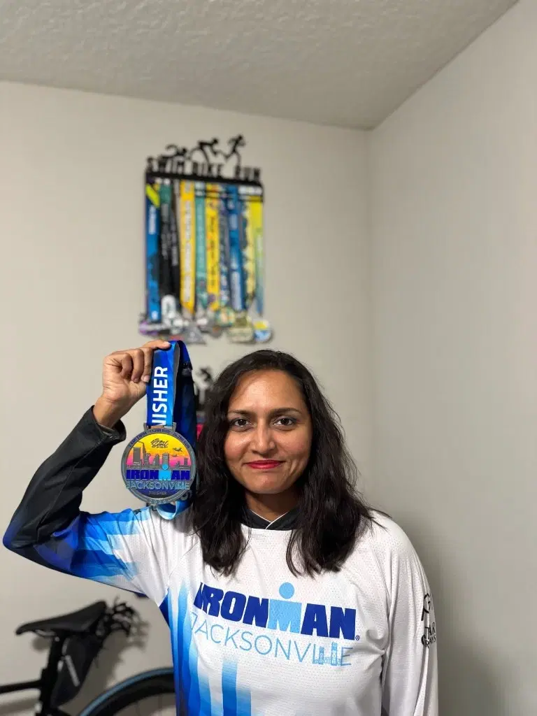 Uma Hazra holding her IRONMAN Jacksonville finisher medal